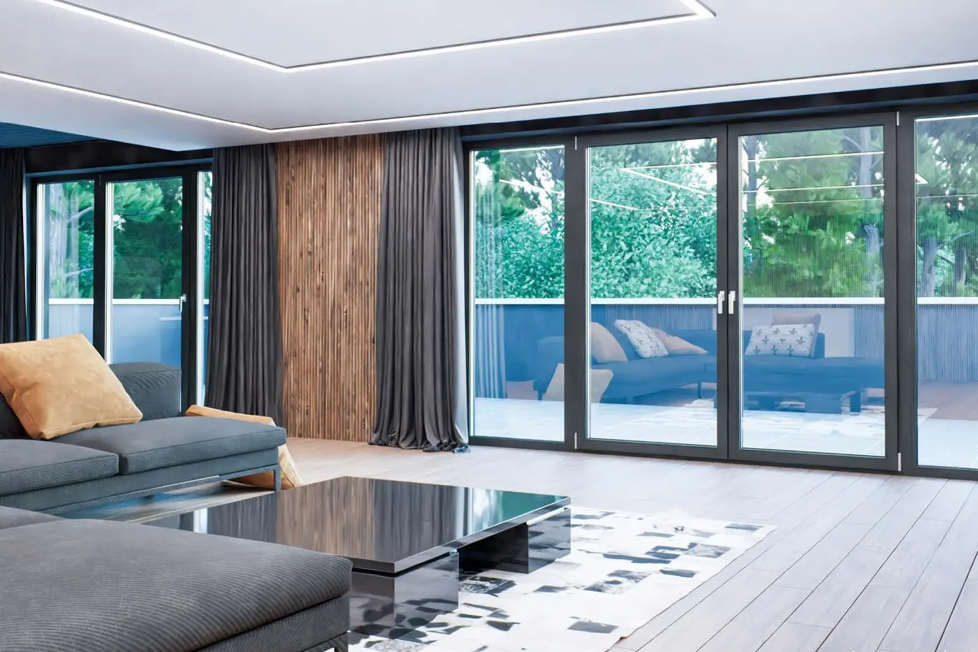 Wohnzimmer mit grauem Sofa und breiter Schiebetür auf eine Terrasse